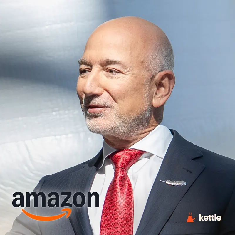 A bald, bearded man in a dark suit and red tie, with the Amazon logo overlaid in the bottom corner