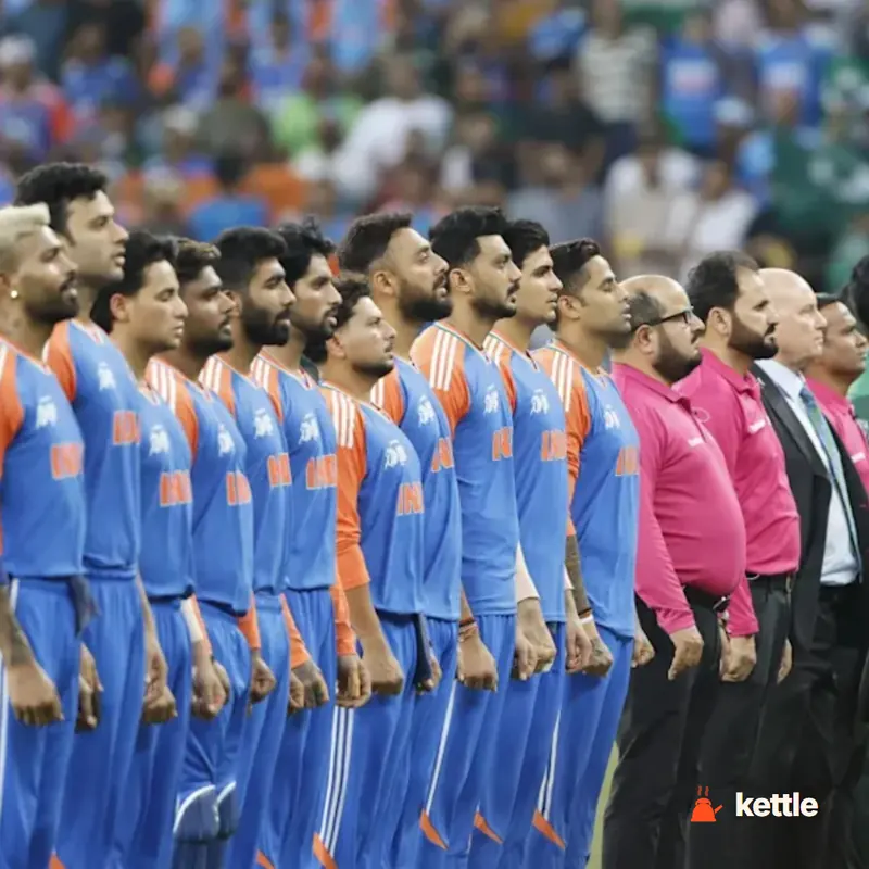 Indian hockey team players in blue/orange kits lined up for the national anthem, with officials beside them
