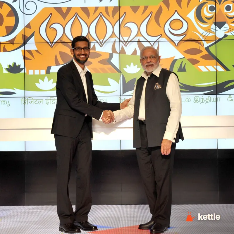 Sundar Pichai shaking hands with Narendra Modi in front of a Google-themed backdrop